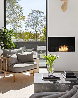 EcoSmart Fire Flex 32LC corner ethanol fireplace warms Long Branch Passive House living room with sleek built-in black feature.